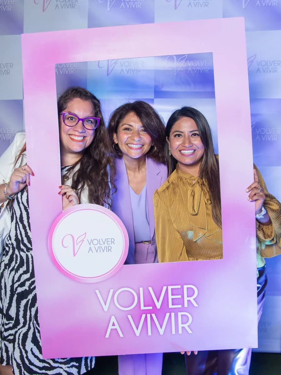 Tres asistentes posan con el marco de Volver a Vivir en el aniversario