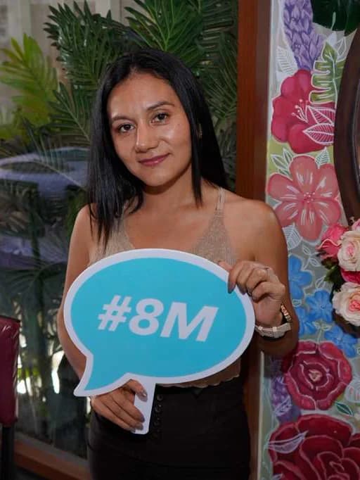 Asistente al brunch sosteniendo un cartel con «#8M»