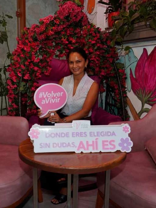 Asistente al brunch bajo el arco de flores con un cartel de «#VolverAVivir»