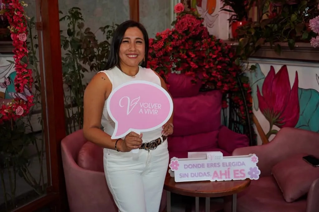 Asistente sonriente con el cartel de Volver a Vivir